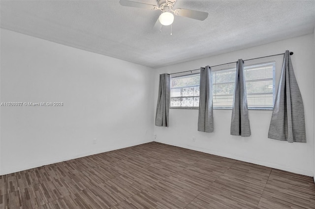 empty room featuring a textured ceiling, dark hardwood / wood-style floors, and ceiling fan