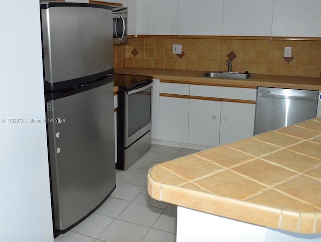 kitchen with white cabinetry, sink, stainless steel appliances, and tile counters