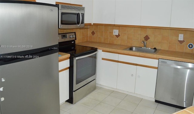 kitchen with decorative backsplash, white cabinetry, sink, and appliances with stainless steel finishes