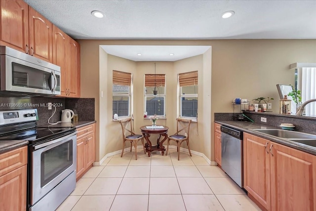 kitchen with tasteful backsplash, sink, light tile patterned floors, and stainless steel appliances