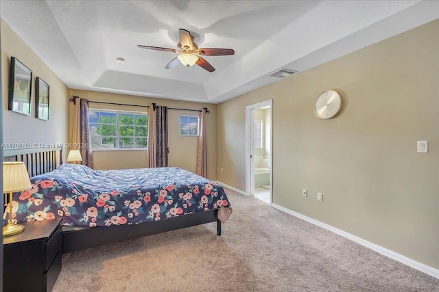 carpeted bedroom with connected bathroom, a raised ceiling, and ceiling fan