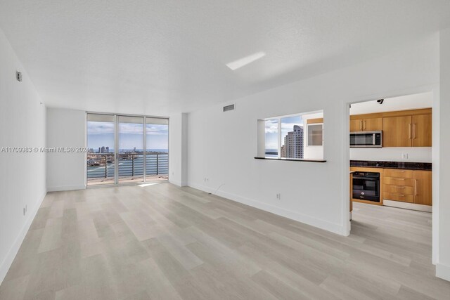 335 S Biscayne Blvd Unit 4109, Miami, FL 33131 - unfurnished living room with expansive windows, light wood finished floors, a textured ceiling, baseboards, and visible vents