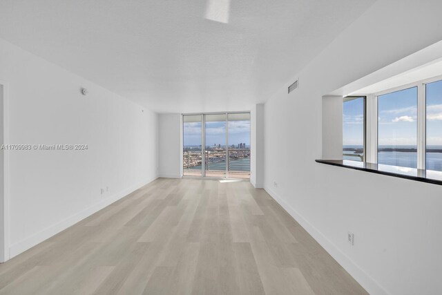 335 S Biscayne Blvd Unit 4109, Miami, FL 33131 - empty room featuring a water view, visible vents, baseboards, expansive windows, and light wood-type flooring