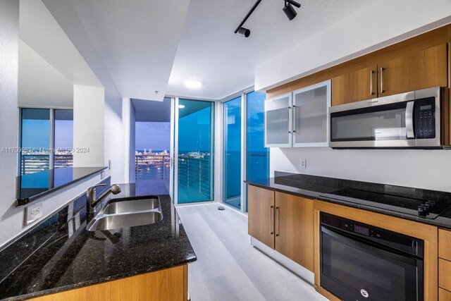 335 S Biscayne Blvd Unit 4109, Miami, FL 33131 - kitchen featuring a sink, dark stone countertops, black appliances, and brown cabinetry