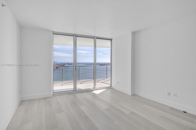 335 S Biscayne Blvd Unit 4109, Miami, FL 33131 - spare room featuring floor to ceiling windows, light wood-style flooring, a water view, and baseboards