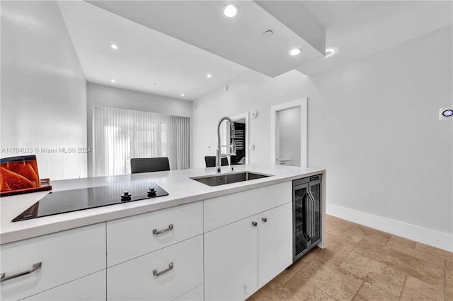 kitchen with white cabinets, black electric cooktop, beverage cooler, and sink