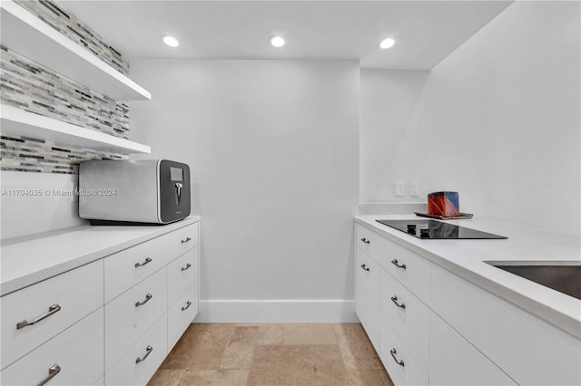 interior space featuring white cabinets, decorative backsplash, and black electric stovetop