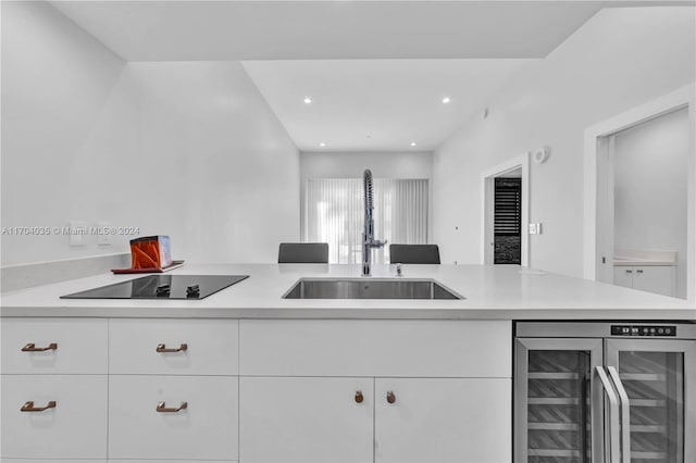 kitchen with white cabinets, black electric stovetop, wine cooler, and sink