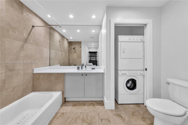 full bathroom featuring tiled shower / bath, stacked washer and dryer, vanity, and toilet