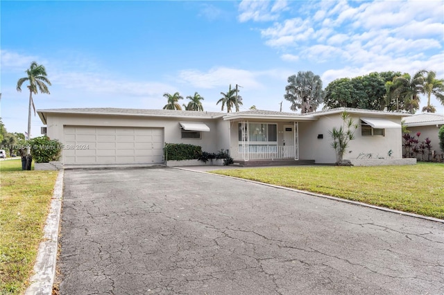 single story home featuring covered porch, a garage, and a front yard