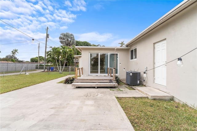 rear view of house with central AC, a yard, and a patio