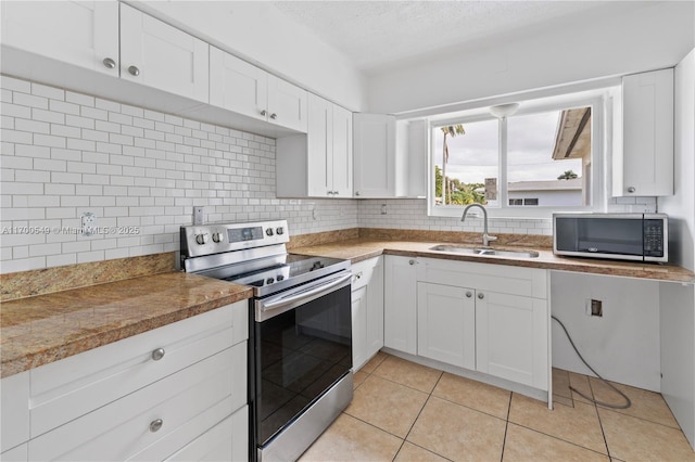 201 Entrada Dr, Hollywood, FL 33021 - kitchen with backsplash, appliances with stainless steel finishes, a sink, light tile patterned floors, and white cabinetry