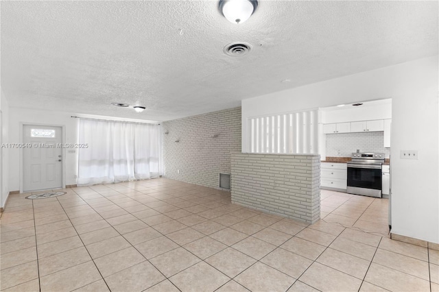 201 Entrada Dr, Hollywood, FL 33021 - unfurnished living room featuring visible vents, a textured ceiling, light tile patterned floors, and brick wall