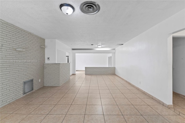 201 Entrada Dr, Hollywood, FL 33021 - empty room featuring a textured ceiling, brick wall, visible vents, a fireplace, and light tile patterned flooring