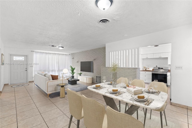 dining space featuring light tile patterned floors, brick wall, and a textured ceiling