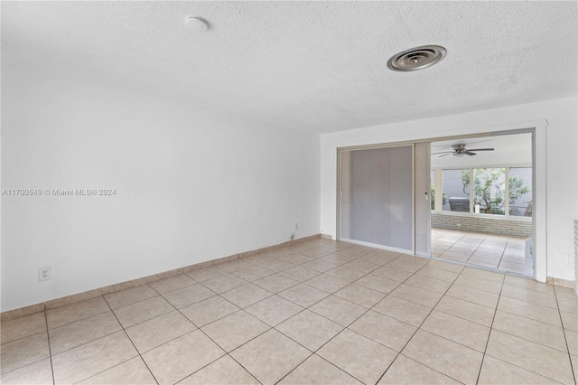 tiled empty room with a textured ceiling and ceiling fan