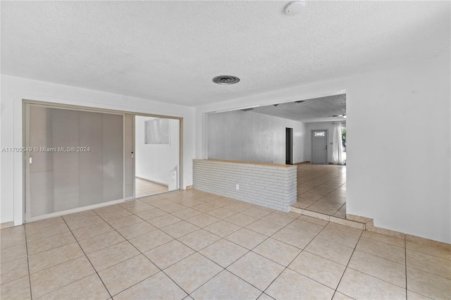 tiled empty room with a textured ceiling