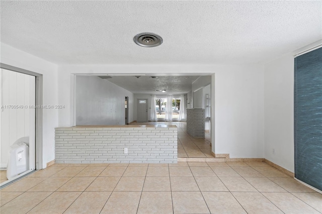 tiled empty room featuring a textured ceiling