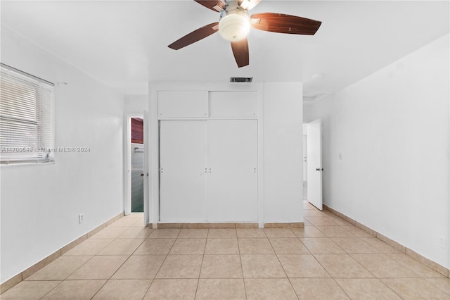 unfurnished bedroom featuring ceiling fan, light tile patterned floors, and a closet