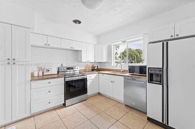 kitchen featuring white cabinets, sink, tasteful backsplash, light tile patterned flooring, and stainless steel appliances