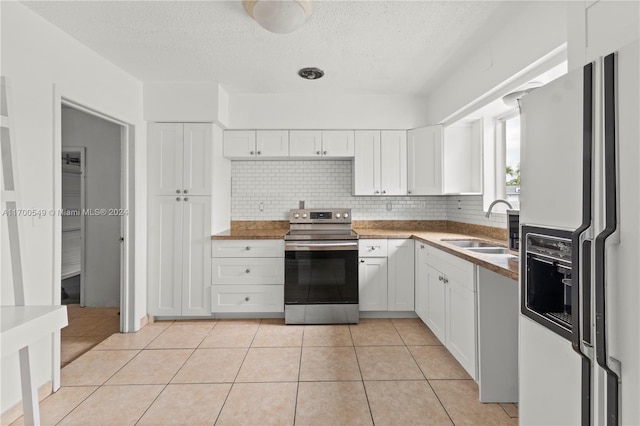 kitchen featuring white refrigerator with ice dispenser, white cabinetry, and stainless steel range with electric cooktop