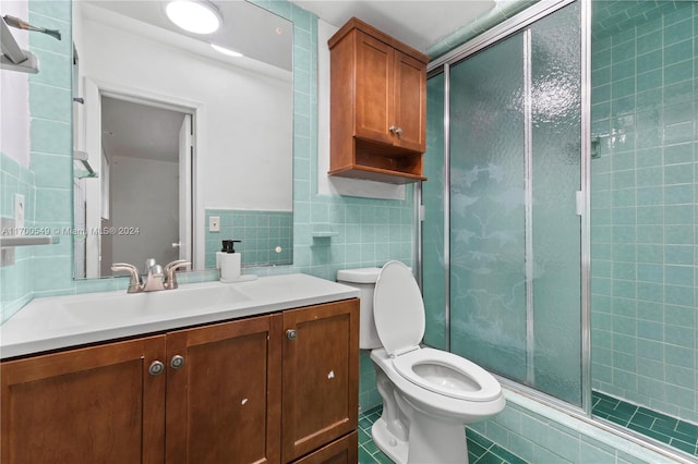 bathroom with tile patterned flooring, vanity, a shower with shower door, and tile walls