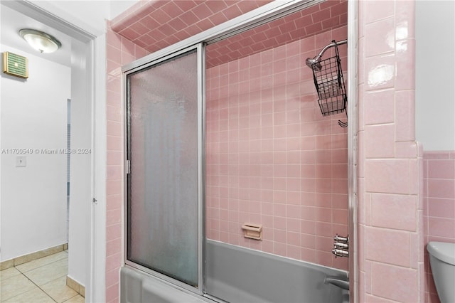 bathroom with tile patterned floors, toilet, and combined bath / shower with glass door