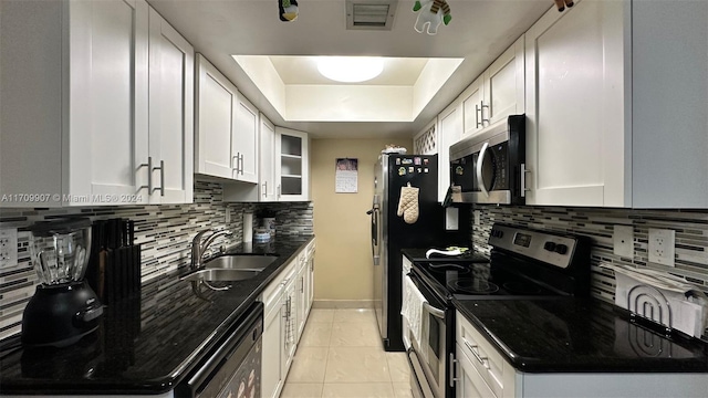 kitchen with white cabinetry, sink, stainless steel appliances, backsplash, and dark stone countertops