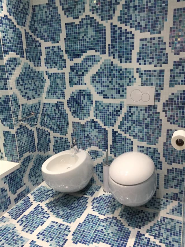 bathroom featuring tile patterned flooring, toilet, tile walls, and a bidet