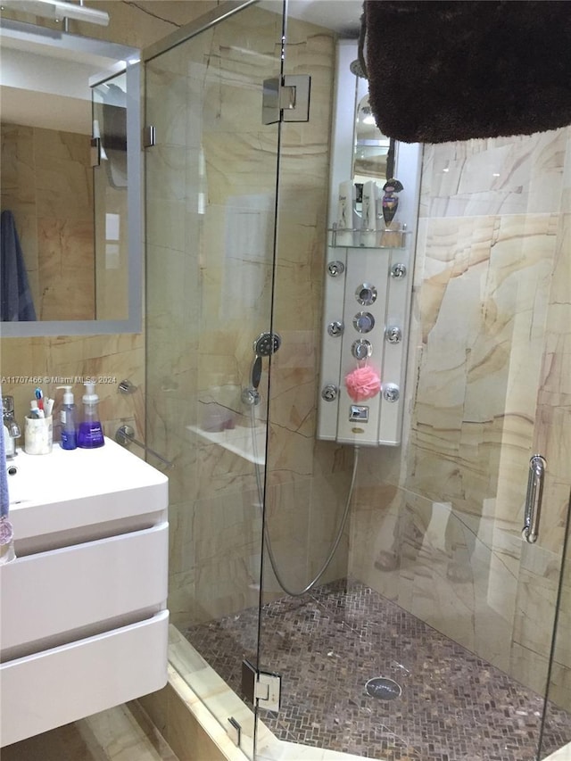 bathroom featuring vanity, backsplash, tile walls, and a shower with shower door