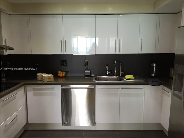 kitchen with dishwasher, backsplash, sink, dark tile patterned floors, and white cabinetry