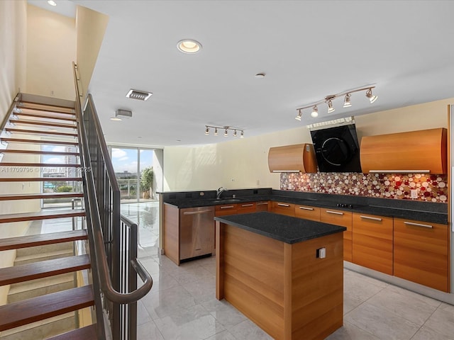 kitchen featuring sink, backsplash, a center island, stainless steel dishwasher, and track lighting