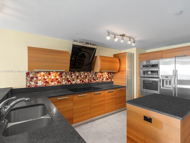 kitchen featuring sink, dark stone countertops, light tile patterned floors, stainless steel appliances, and range hood