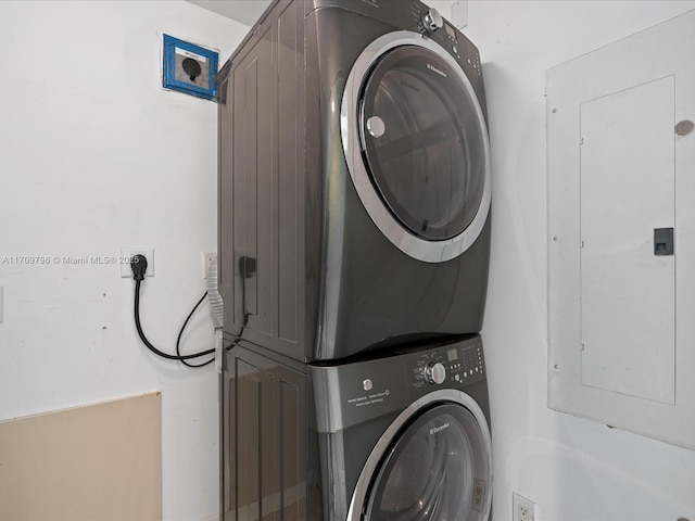 clothes washing area featuring stacked washer and dryer and electric panel