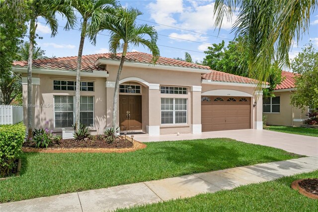 mediterranean / spanish-style home featuring a front lawn and a garage