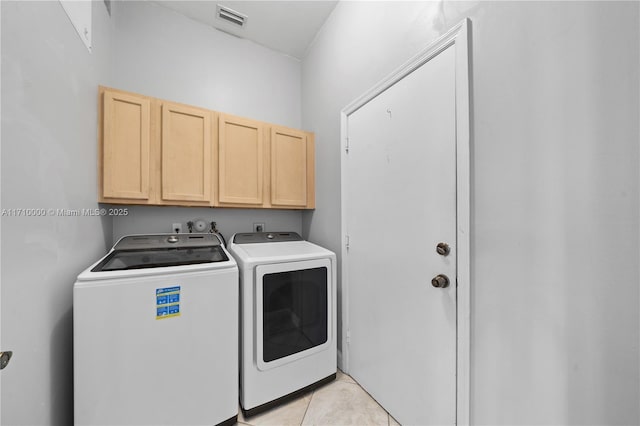 washroom with washer and dryer, cabinets, and light tile patterned floors