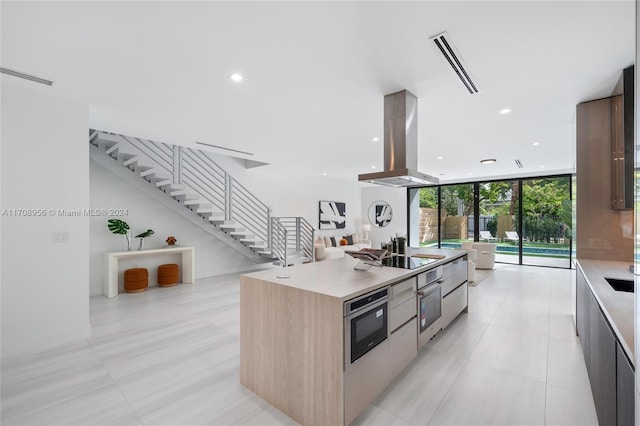 kitchen featuring island exhaust hood, expansive windows, stainless steel oven, black electric cooktop, and light brown cabinets