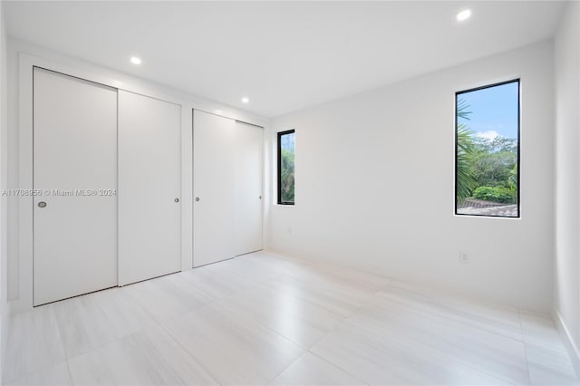 unfurnished bedroom with two closets, multiple windows, and light tile patterned flooring