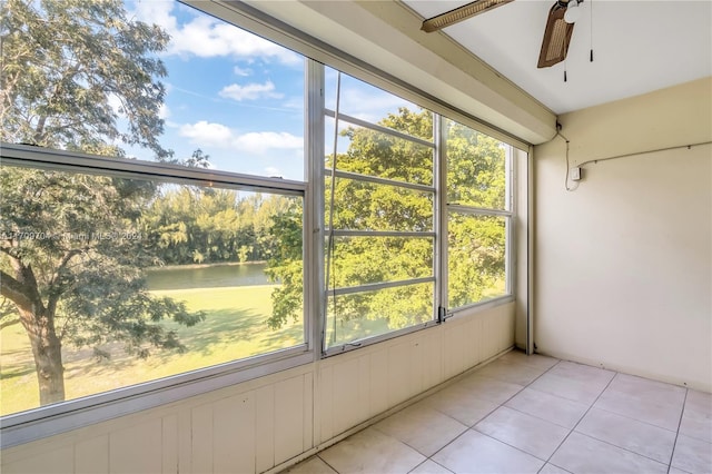 unfurnished sunroom featuring ceiling fan and a water view