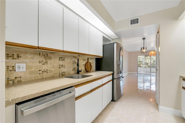 kitchen featuring appliances with stainless steel finishes, backsplash, sink, pendant lighting, and white cabinetry