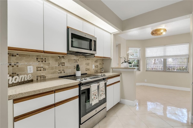 kitchen featuring white cabinetry, light stone countertops, stainless steel appliances, tasteful backsplash, and light tile patterned floors