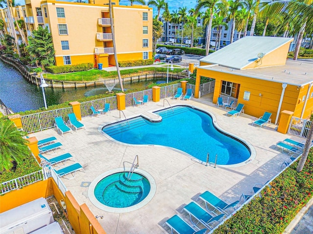 view of swimming pool featuring a patio, a water view, and a hot tub