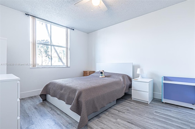 bedroom with a textured ceiling, light wood-type flooring, and ceiling fan