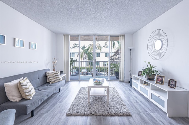 living room with wood-type flooring, a textured ceiling, and a wall of windows