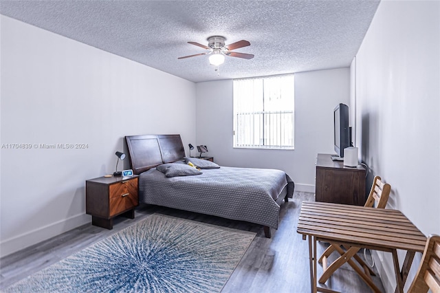 bedroom with hardwood / wood-style floors, ceiling fan, and a textured ceiling