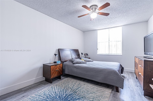 bedroom featuring ceiling fan, light hardwood / wood-style flooring, and a textured ceiling