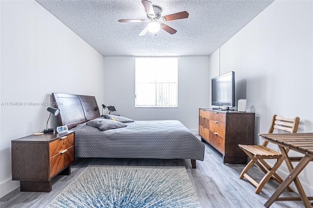 bedroom with ceiling fan, a textured ceiling, and hardwood / wood-style flooring