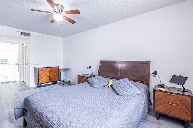 bedroom featuring ceiling fan, light hardwood / wood-style floors, and a textured ceiling