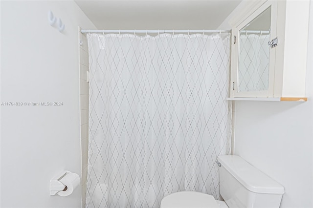 bathroom featuring curtained shower and toilet