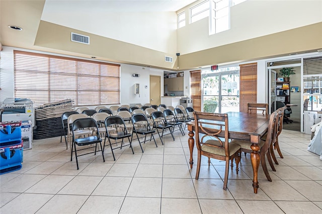 dining room with light tile patterned flooring and a high ceiling